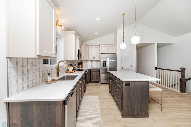 kitchen with a breakfast bar area, light wood-style flooring, a sink, light countertops, and appliances with stainless steel finishes