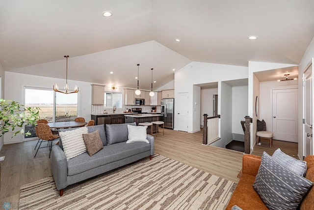 living area with vaulted ceiling, recessed lighting, an inviting chandelier, and light wood-style floors