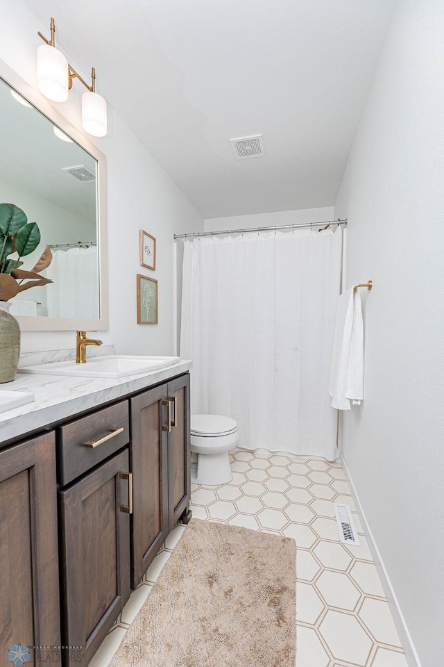 full bathroom featuring toilet, vanity, and visible vents