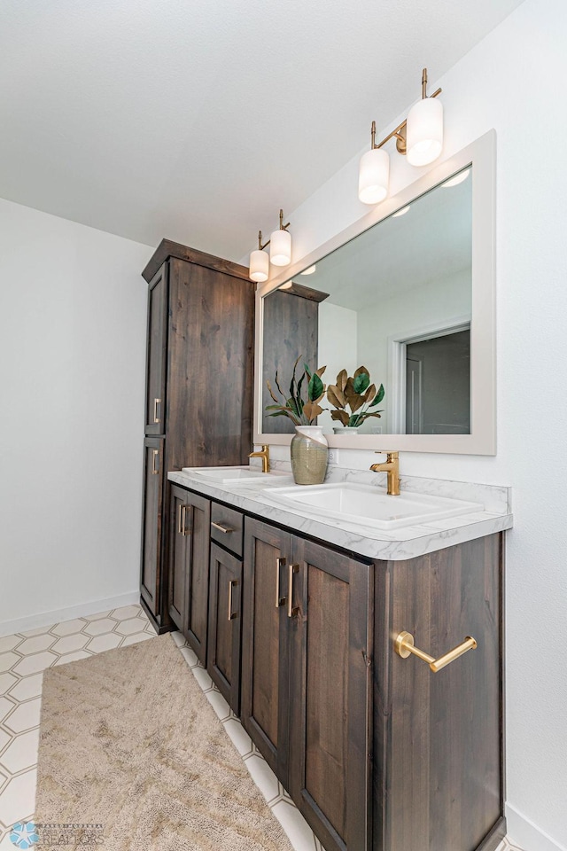 full bath with double vanity, a sink, and baseboards