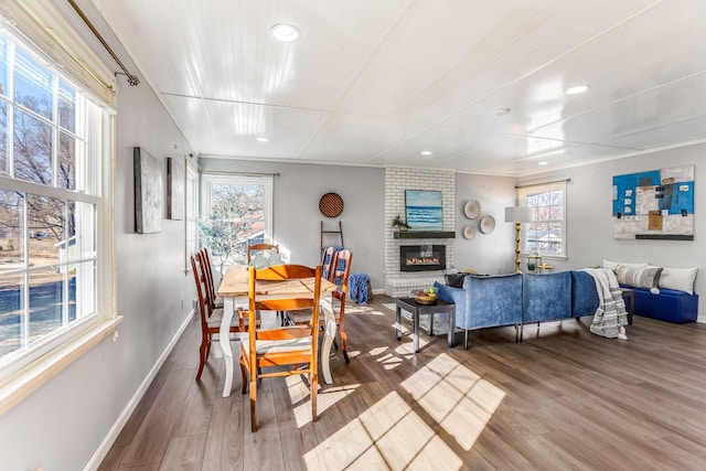 dining space with a brick fireplace, wood finished floors, and a wealth of natural light