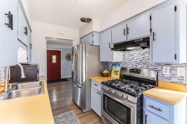 kitchen with light wood finished floors, light countertops, appliances with stainless steel finishes, a sink, and under cabinet range hood