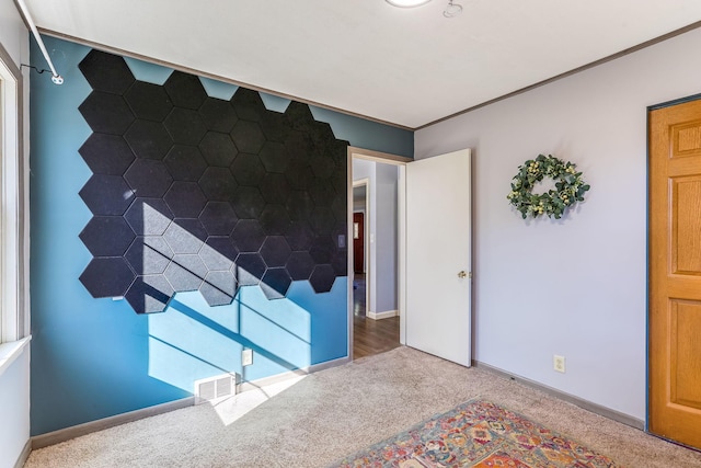 unfurnished bedroom featuring baseboards, visible vents, crown molding, and carpet flooring