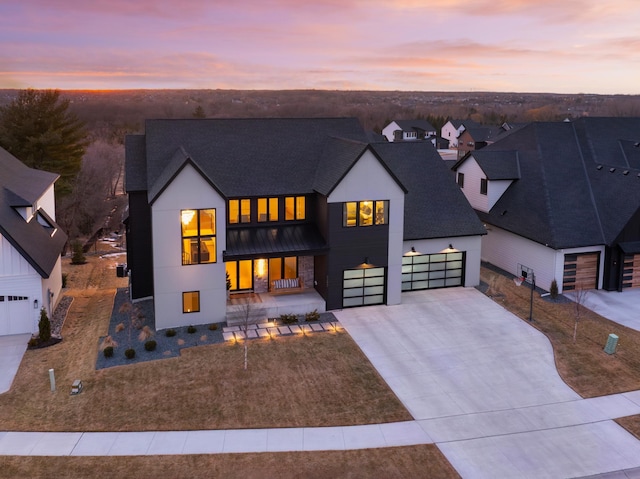 modern farmhouse style home featuring an attached garage, a porch, roof with shingles, stucco siding, and driveway