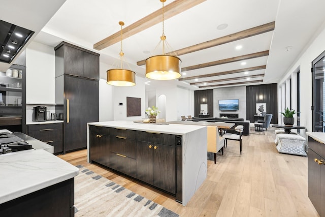 kitchen featuring beamed ceiling, light wood finished floors, decorative light fixtures, a kitchen island, and light countertops