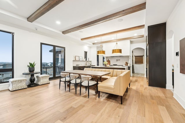 interior space with baseboards, beam ceiling, light wood-style flooring, recessed lighting, and arched walkways