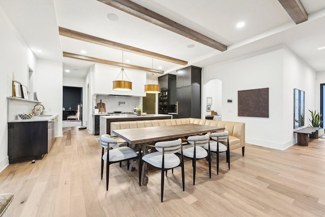 dining room featuring baseboards, beam ceiling, recessed lighting, arched walkways, and light wood-type flooring