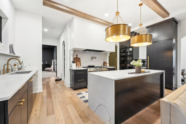 kitchen featuring beamed ceiling, light wood-style floors, arched walkways, and a sink