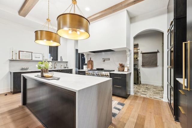 kitchen featuring beamed ceiling, tasteful backsplash, light wood-style flooring, and light countertops