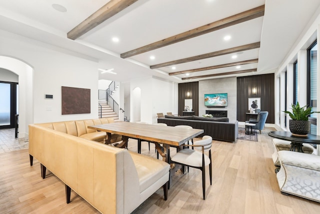 dining room with stairs, light wood-style flooring, and arched walkways