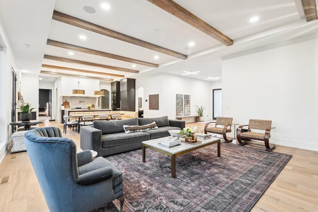 living area featuring baseboards, recessed lighting, arched walkways, light wood-style floors, and beamed ceiling