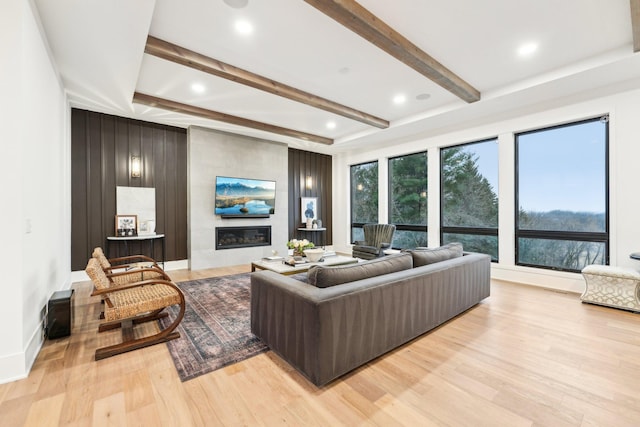 living area featuring light wood-type flooring, beamed ceiling, recessed lighting, a large fireplace, and baseboards