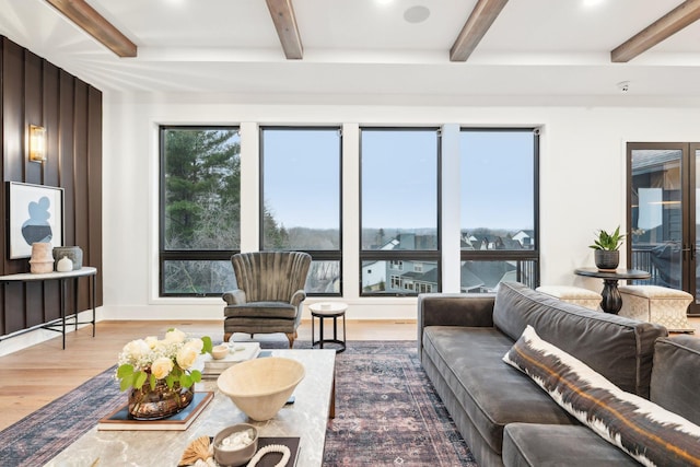 living room featuring beamed ceiling, wood finished floors, and baseboards