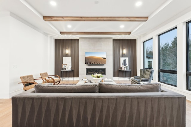 living area with beamed ceiling, light wood-style flooring, and a fireplace