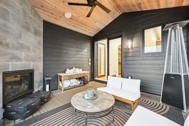 interior space with wooden ceiling, vaulted ceiling, wood finished floors, and a tile fireplace