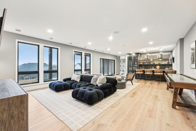 living area featuring recessed lighting, light wood-style flooring, and a dry bar