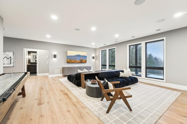 living area with recessed lighting, baseboards, and light wood-style flooring