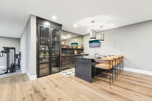 bar featuring light wood-type flooring, decorative light fixtures, recessed lighting, baseboards, and wet bar