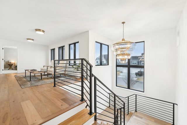 stairway with an inviting chandelier and wood finished floors