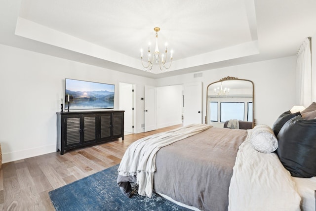 bedroom featuring a chandelier, a tray ceiling, and wood finished floors