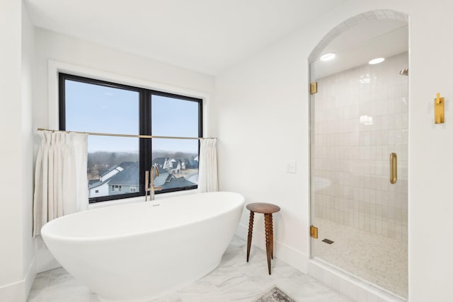 bathroom featuring marble finish floor, a shower stall, baseboards, and a freestanding tub