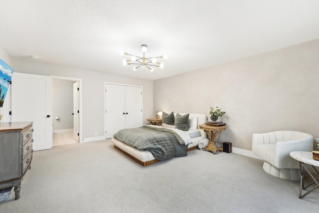 bedroom featuring a textured ceiling, a closet, an inviting chandelier, carpet flooring, and baseboards