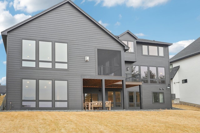 back of property featuring a lawn and a sunroom