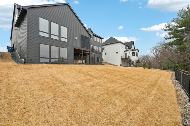 rear view of house with a lawn and fence