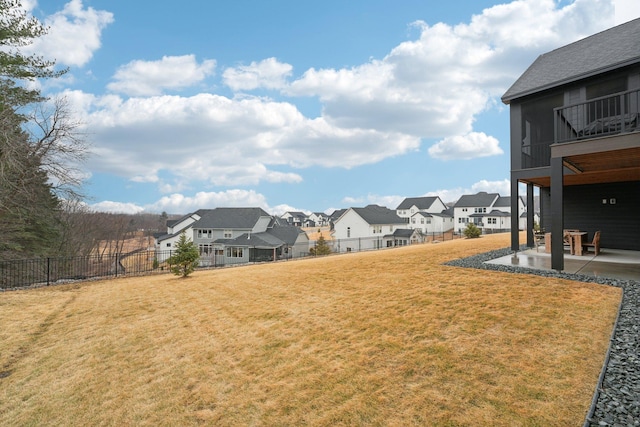 view of yard featuring a patio, a balcony, fence, and a residential view