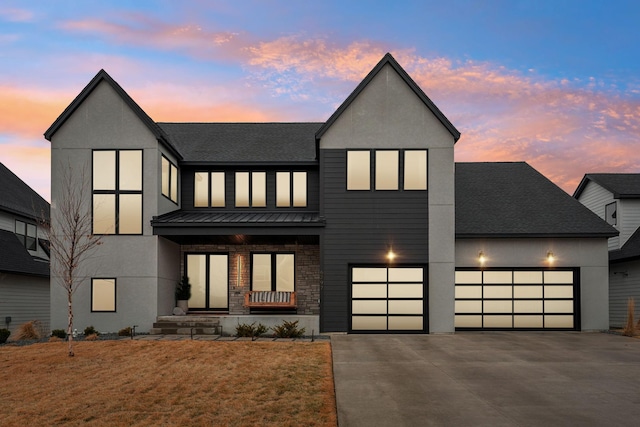 view of front facade featuring roof with shingles, a standing seam roof, an attached garage, concrete driveway, and metal roof