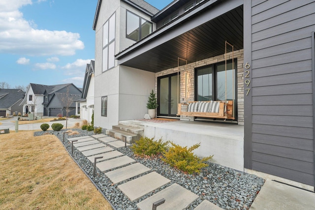 property entrance featuring covered porch, a residential view, and stucco siding