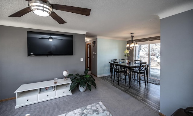 dining area featuring a textured ceiling, ceiling fan with notable chandelier, and baseboards