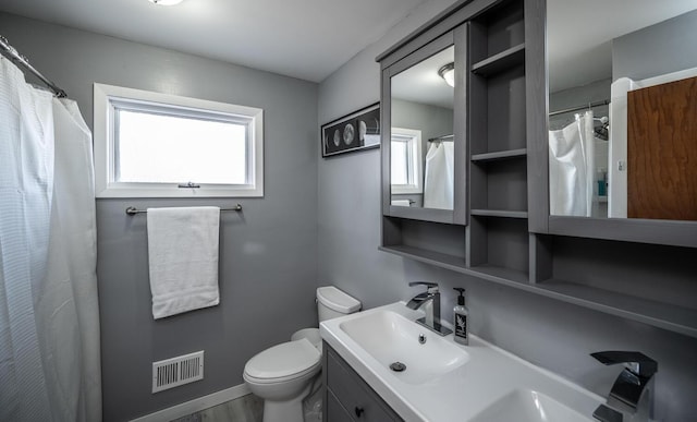 bathroom with baseboards, visible vents, a shower with shower curtain, toilet, and vanity