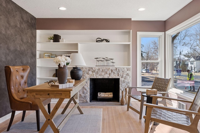 living area featuring recessed lighting, a fireplace, and light wood finished floors