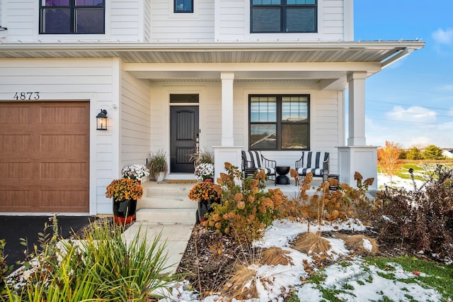 doorway to property with an attached garage and covered porch