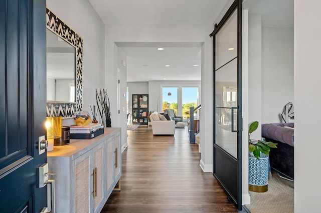 corridor with recessed lighting, dark wood finished floors, and a barn door