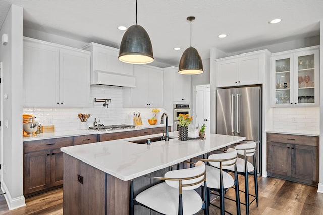 kitchen featuring appliances with stainless steel finishes, a sink, dark wood finished floors, and a kitchen breakfast bar