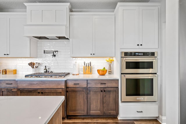 kitchen featuring appliances with stainless steel finishes, light countertops, dark wood finished floors, and tasteful backsplash