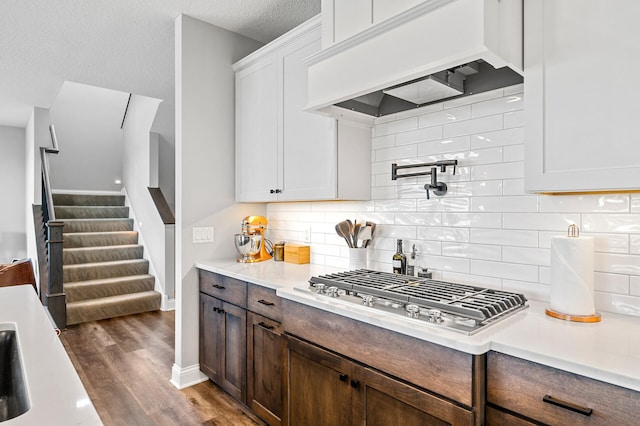 kitchen with dark wood-type flooring, light countertops, custom range hood, and stainless steel gas stovetop