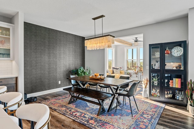 dining room with an accent wall, baseboards, and wood finished floors