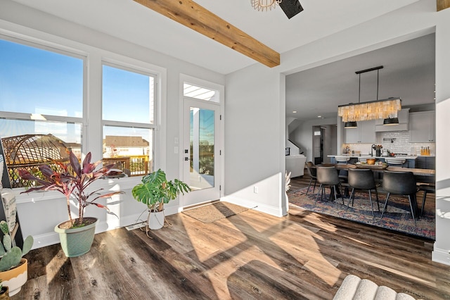 dining area featuring wood finished floors, beam ceiling, and baseboards