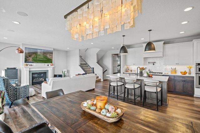 dining space with recessed lighting, stairs, wood finished floors, and a glass covered fireplace