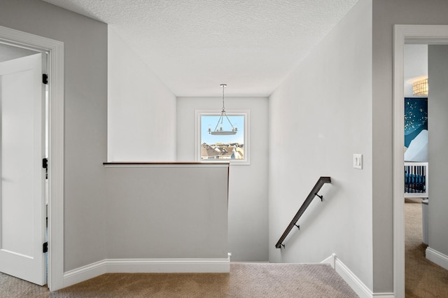 stairway with carpet floors, baseboards, and a textured ceiling