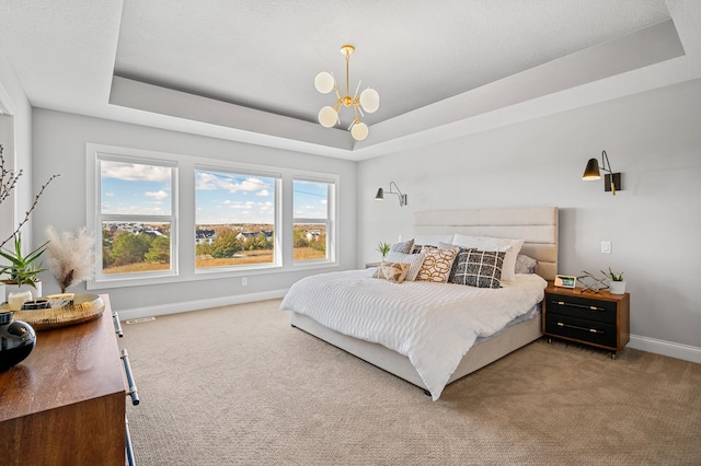 bedroom featuring a notable chandelier, a tray ceiling, carpet flooring, and baseboards