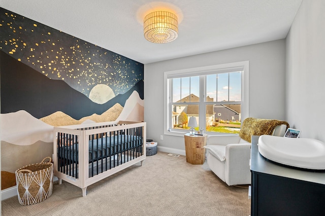 carpeted bedroom with visible vents, an accent wall, a crib, baseboards, and wallpapered walls