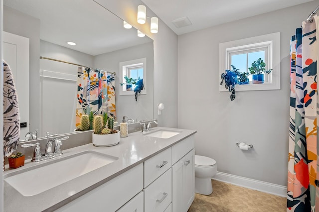 bathroom with toilet, a sink, baseboards, and double vanity