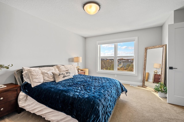 bedroom featuring visible vents, a textured ceiling, baseboards, and carpet flooring