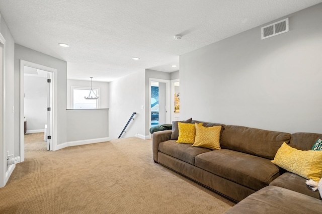 carpeted living area with baseboards, visible vents, a textured ceiling, and recessed lighting