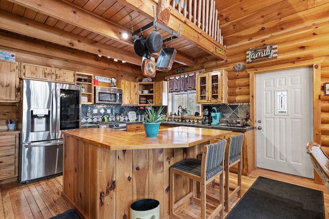 kitchen featuring stainless steel appliances, wooden counters, light wood-style floors, glass insert cabinets, and a kitchen island