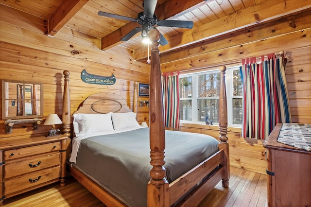 bedroom featuring wood walls, wood ceiling, light wood-style floors, and beamed ceiling